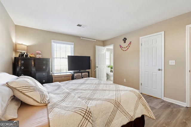 bedroom featuring light wood-type flooring and connected bathroom