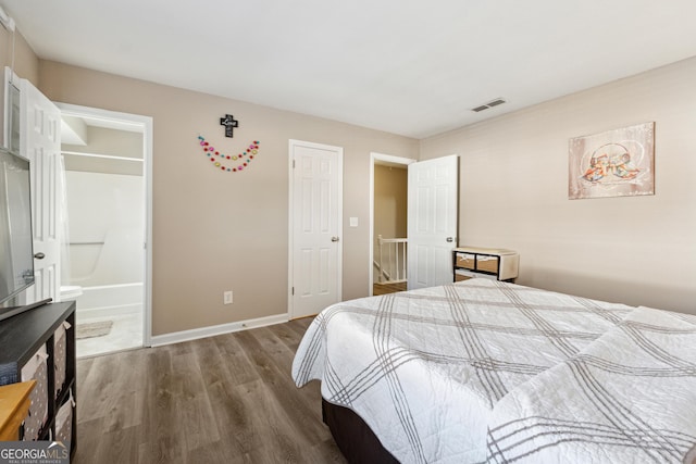 bedroom with wood-type flooring and ensuite bath