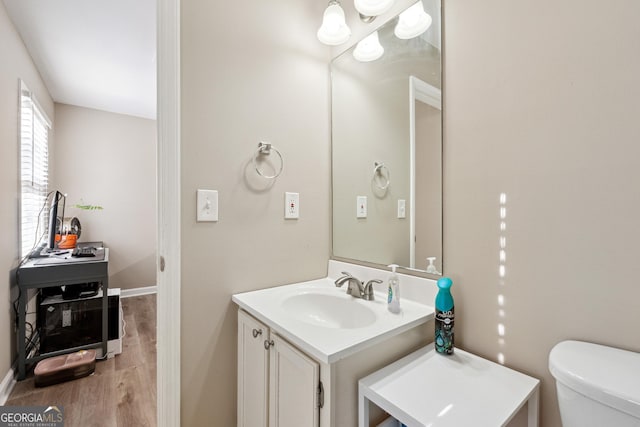 bathroom with hardwood / wood-style floors, vanity, and toilet