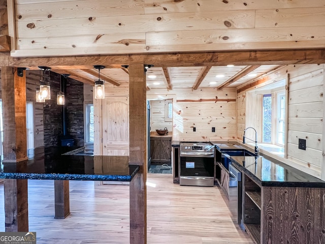 kitchen with wooden walls, decorative light fixtures, wooden ceiling, stainless steel range oven, and light hardwood / wood-style floors