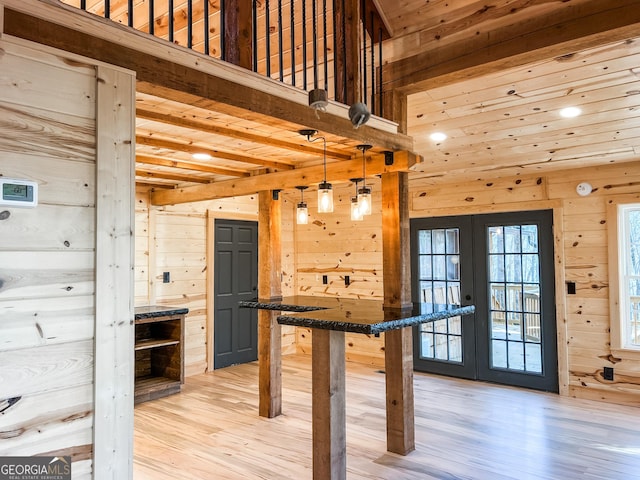 interior space with french doors, light wood-type flooring, wooden walls, and beam ceiling