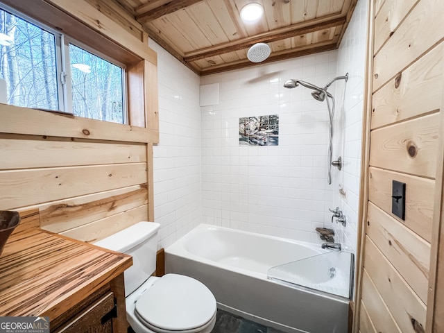 bathroom with tiled shower / bath combo, toilet, wooden walls, and wood ceiling