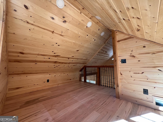 additional living space with hardwood / wood-style floors, wood walls, wooden ceiling, and vaulted ceiling