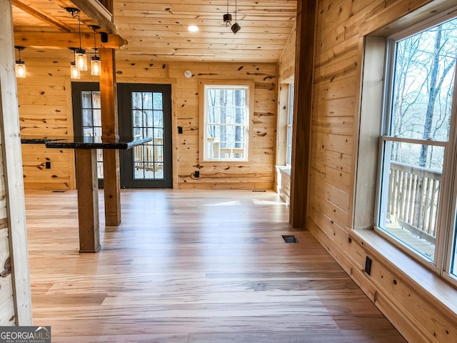 entryway featuring light wood-type flooring, wooden walls, and wood ceiling