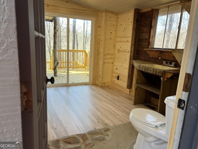 bathroom with sink, wooden ceiling, toilet, lofted ceiling, and wood walls