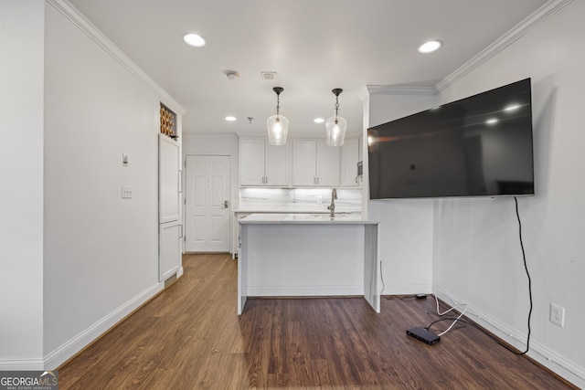 kitchen with a peninsula, dark wood-style flooring, white cabinets, light countertops, and crown molding