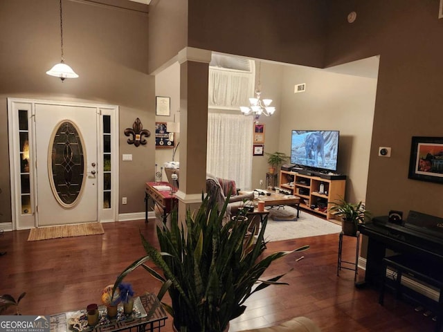 foyer entrance with a towering ceiling, dark hardwood / wood-style floors, and a notable chandelier