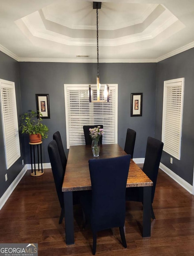 dining area featuring dark hardwood / wood-style floors, a raised ceiling, and crown molding