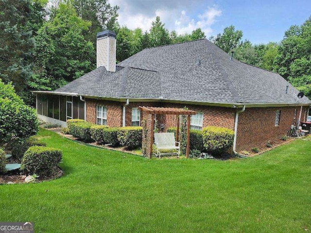 back of property with a lawn, a sunroom, and a pergola