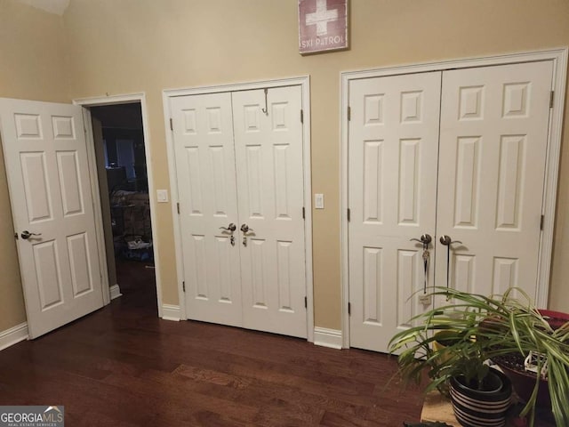 unfurnished bedroom with dark wood-type flooring and multiple closets