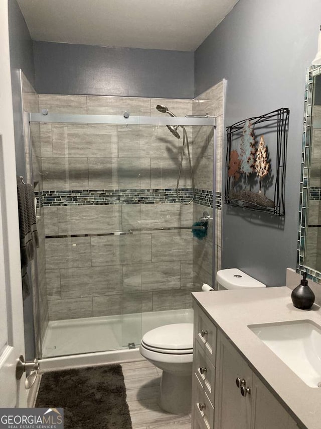 bathroom featuring walk in shower, vanity, and toilet