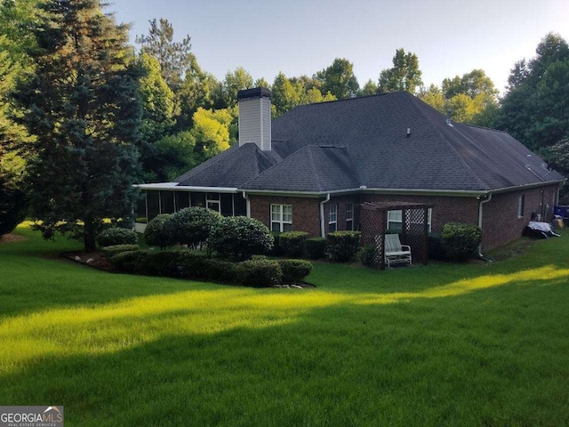 rear view of property with a sunroom and a yard