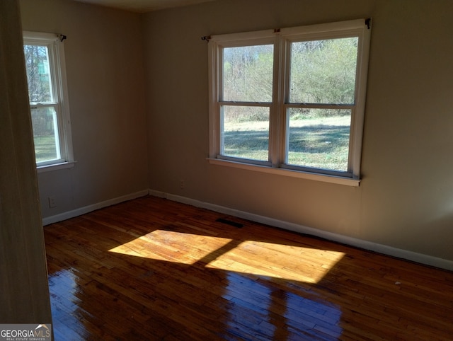 unfurnished room with plenty of natural light and dark hardwood / wood-style floors