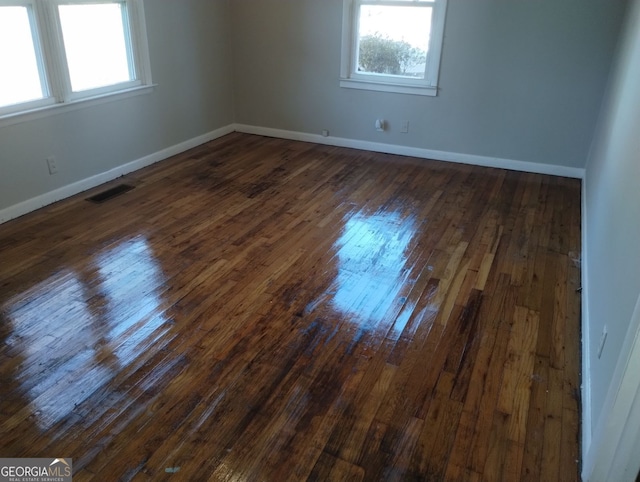 spare room featuring a healthy amount of sunlight and dark hardwood / wood-style floors