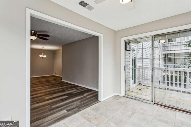 empty room featuring a textured ceiling and ceiling fan with notable chandelier