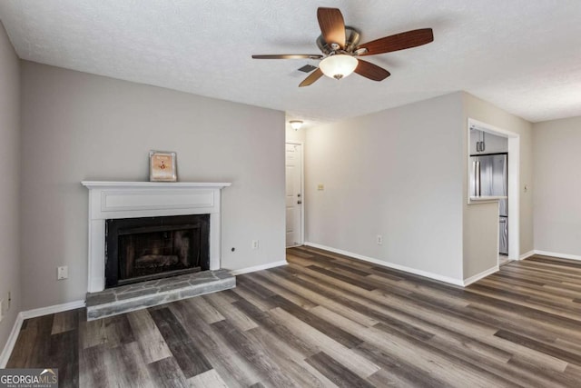 unfurnished living room featuring ceiling fan, dark hardwood / wood-style floors, and a textured ceiling