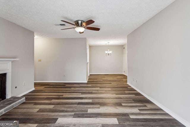 unfurnished living room with ceiling fan with notable chandelier, dark hardwood / wood-style floors, and a textured ceiling