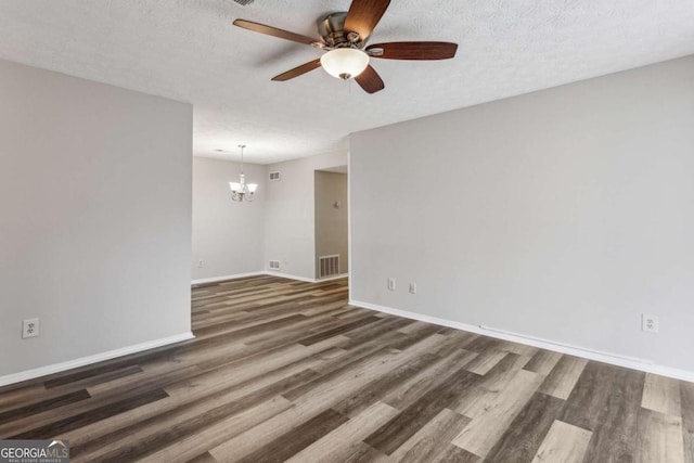 spare room with ceiling fan with notable chandelier, dark hardwood / wood-style floors, and a textured ceiling