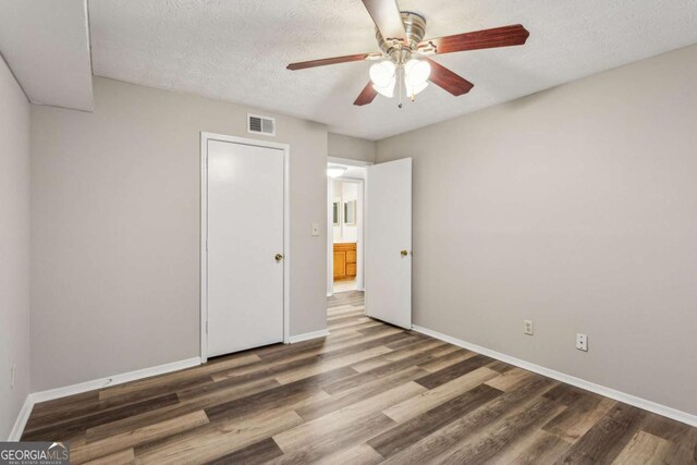 unfurnished bedroom featuring wood-type flooring, a textured ceiling, and ceiling fan