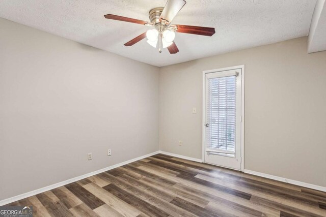 empty room featuring ceiling fan, dark wood-type flooring, and a textured ceiling