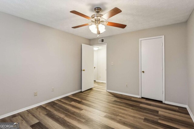 unfurnished bedroom featuring a textured ceiling, dark hardwood / wood-style floors, and ceiling fan