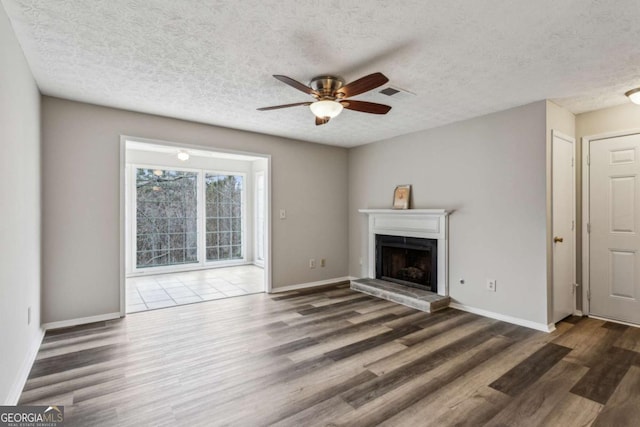 unfurnished living room featuring a textured ceiling, ceiling fan, and dark wood-type flooring