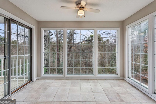 unfurnished sunroom featuring ceiling fan and plenty of natural light