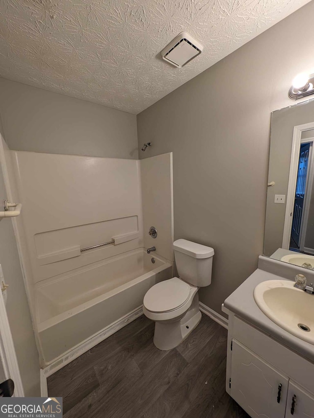 full bathroom featuring toilet, wood-type flooring, a textured ceiling, shower / bathtub combination, and vanity