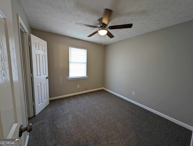 spare room featuring ceiling fan, dark carpet, and a textured ceiling