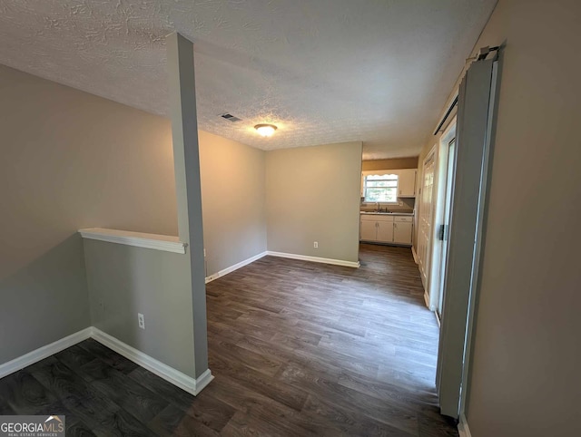 unfurnished room featuring a textured ceiling and dark hardwood / wood-style floors