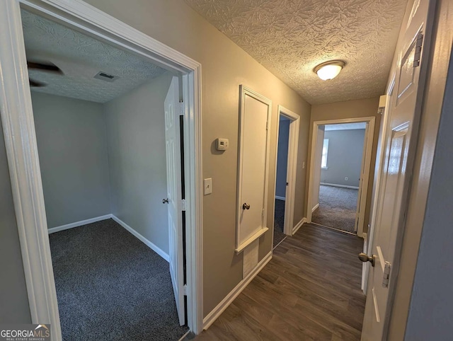 hallway featuring a textured ceiling and dark hardwood / wood-style flooring