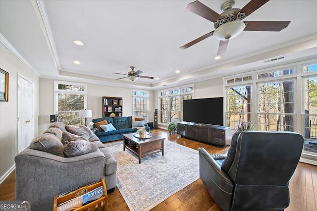 living room featuring plenty of natural light, dark hardwood / wood-style floors, and a tray ceiling