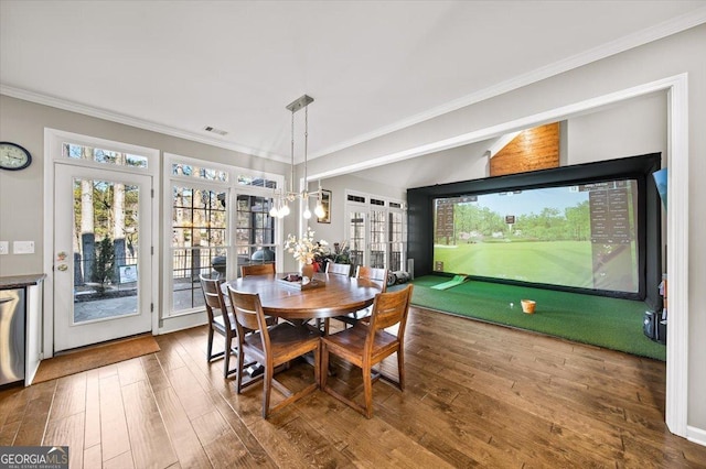 dining area with hardwood / wood-style flooring, golf simulator, ornamental molding, and a chandelier