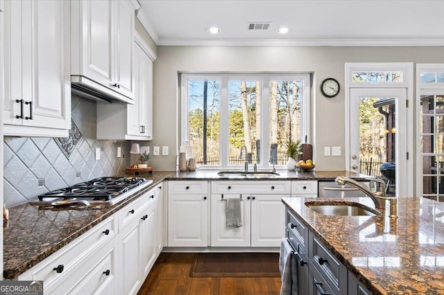 kitchen with decorative backsplash, dark stone countertops, white cabinetry, and sink