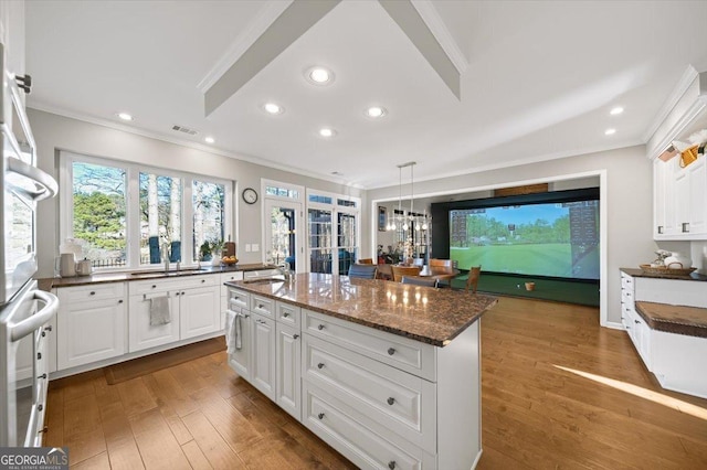 kitchen featuring dark stone counters, white cabinetry, a kitchen island, and hanging light fixtures