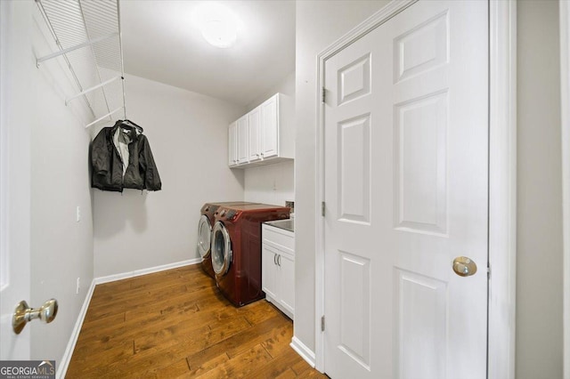 laundry room featuring hardwood / wood-style floors, washer and dryer, and cabinets