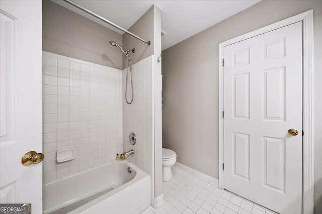 bathroom featuring tile patterned flooring, tiled shower / bath combo, and toilet