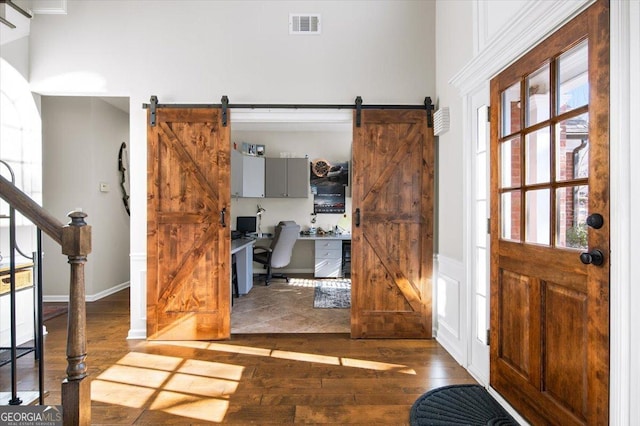 entryway featuring a barn door, built in desk, and dark wood-type flooring