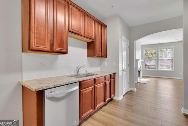 kitchen featuring stainless steel dishwasher, light stone countertops, sink, and light hardwood / wood-style flooring