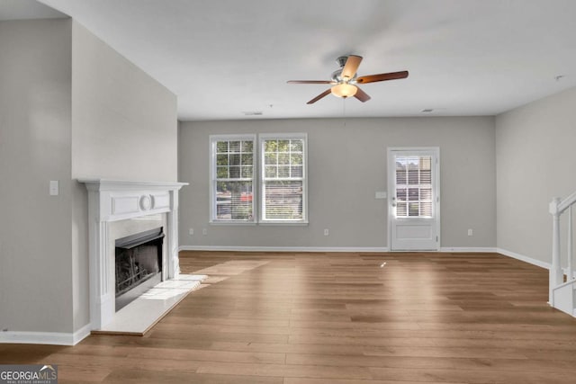 unfurnished living room with a high end fireplace, hardwood / wood-style floors, and ceiling fan