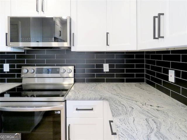 kitchen featuring decorative backsplash, white cabinetry, and appliances with stainless steel finishes