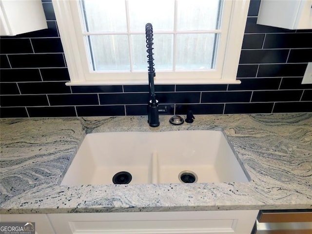 details featuring light stone countertops, white cabinets, and sink