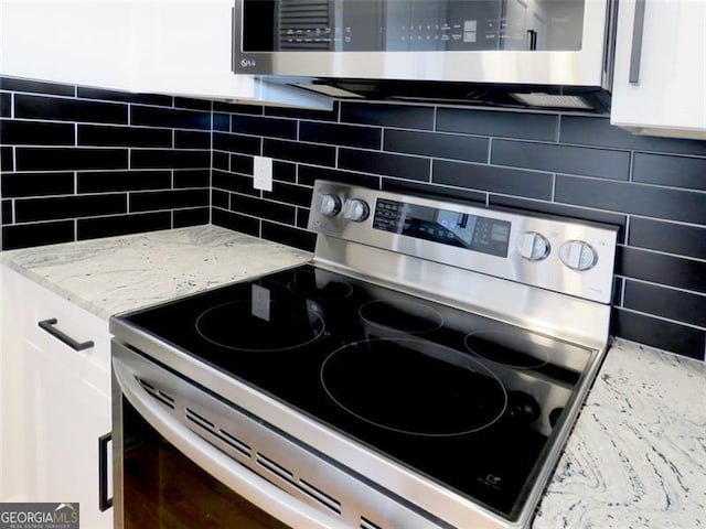 kitchen with decorative backsplash, light stone counters, white cabinetry, and stainless steel appliances