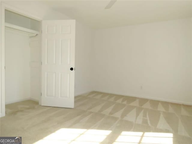 unfurnished bedroom with ceiling fan, a closet, and light colored carpet