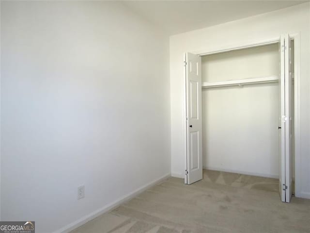 unfurnished bedroom featuring a closet and light colored carpet