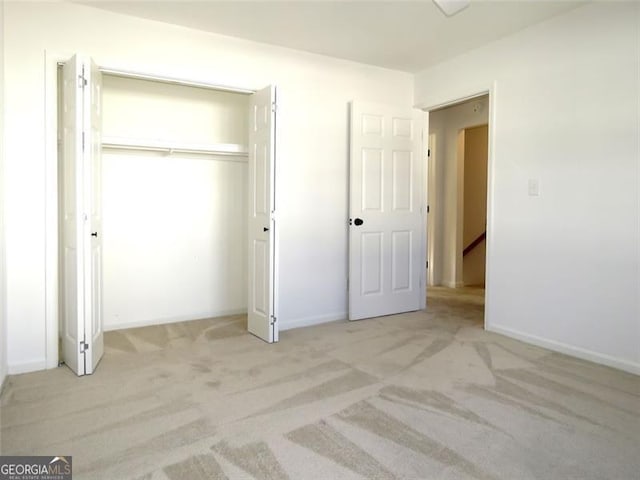 unfurnished bedroom featuring light colored carpet and a closet