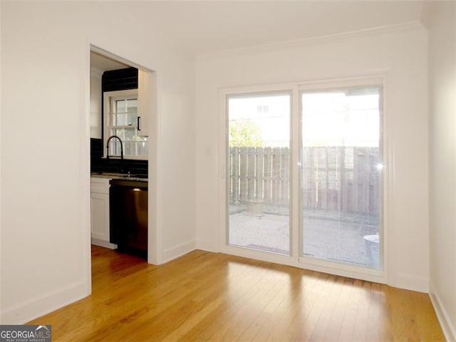 interior space featuring light wood-type flooring, crown molding, and sink