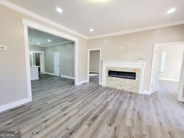 unfurnished living room featuring a stone fireplace, ornamental molding, and light hardwood / wood-style flooring