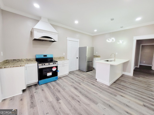 kitchen with stove, premium range hood, white cabinets, stainless steel fridge, and decorative light fixtures