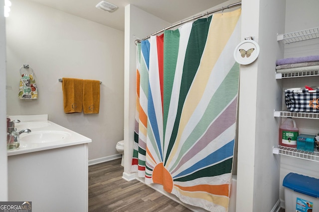 bathroom with visible vents, toilet, a sink, wood finished floors, and baseboards